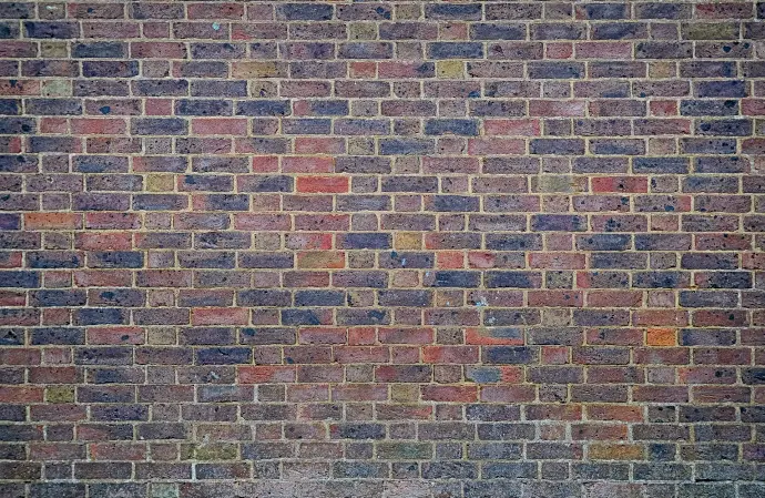 a man sitting on a bench in front of a brick wall
